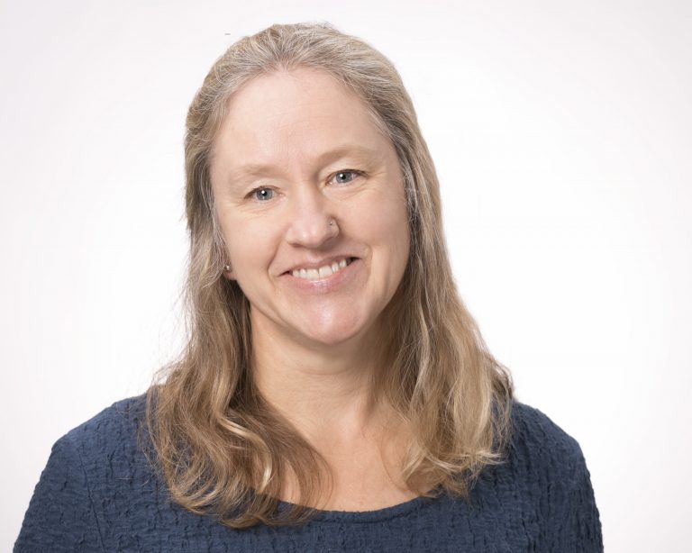Michelle Avery Ferguson, smiling, with shoulder-length blond hair and a navy top.